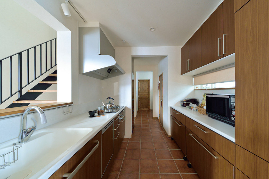 バスルームまで一本の動線で結んだキッチンは、タイル張りの床が印象的。収納が充実したシステムキッチンも使い勝手抜群