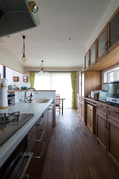 キッチンの背面には木質感を生かした造作収納を設置。カウンターには横長の開口を設け、明るさと眺望を確保