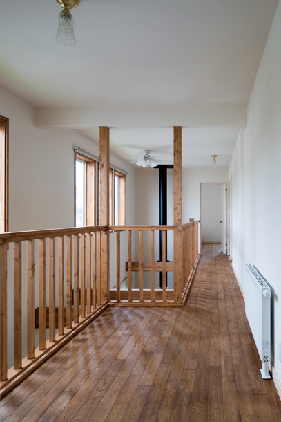 2階の階段ホール、廊下にもナラ無垢床を採用。手すりはパイン材で造作し、床と色を合わせた