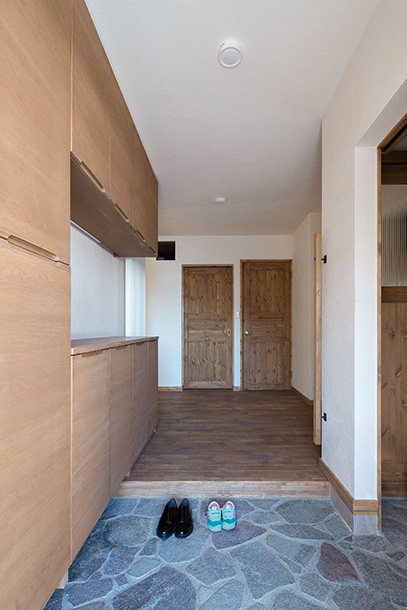 鉄平石張り玄関土間は床暖房を採用。造作玄関収納のほか、土間続きに家族用のシューズクロークを別途設けた