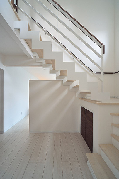 白を基調にした空間に描かれるスケルトン階段の幾何学的なラインが美しい1階ホール。階段下の空間は、収納スペースとしてしっかり活用